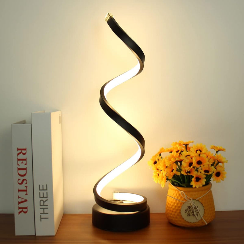 Spiral table lamp close-up of the curved metal spiral with warm light switched on decorative table lamp